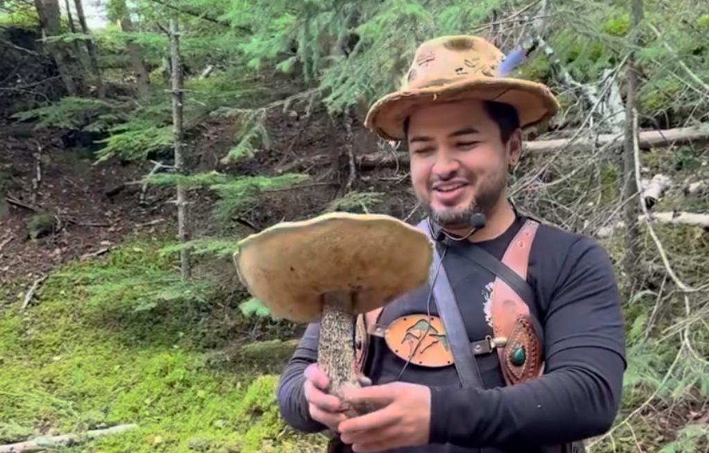 a man in a hat holds a mushroom