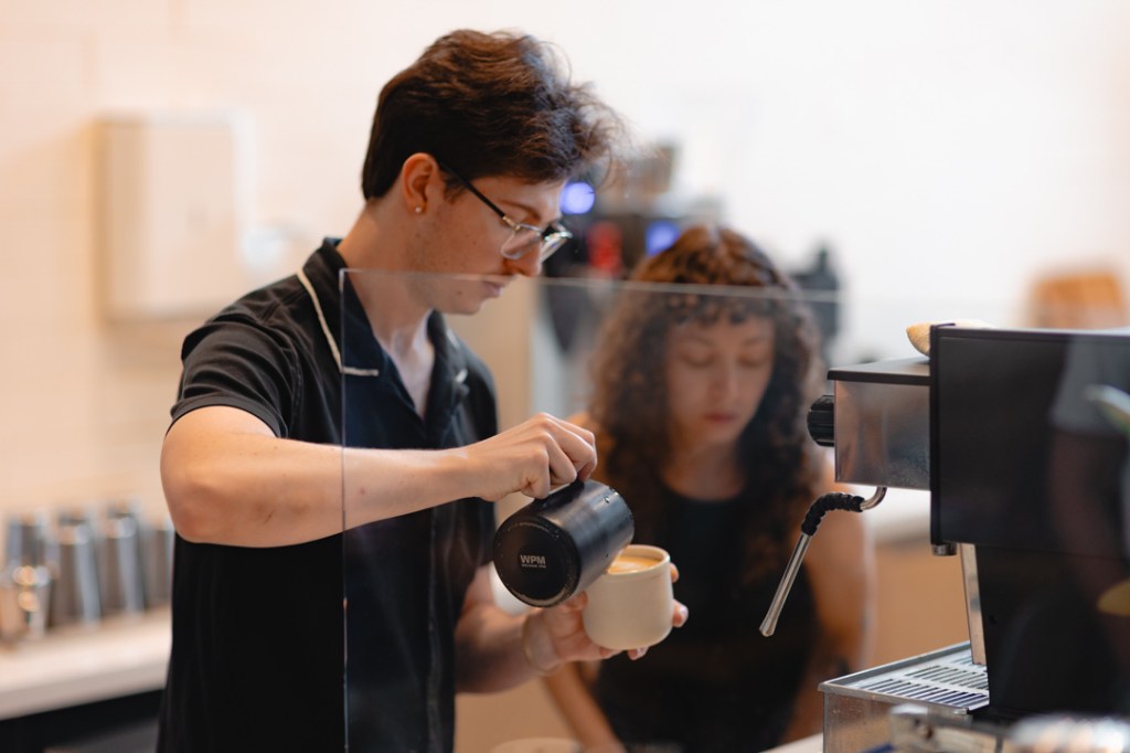 Two baristas making drinks at a coffee bar.