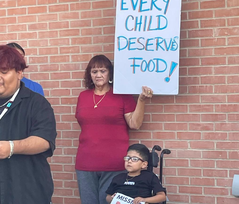 a woman holds a sign that says "every child deserves food" next to a young boy in a wheelchair