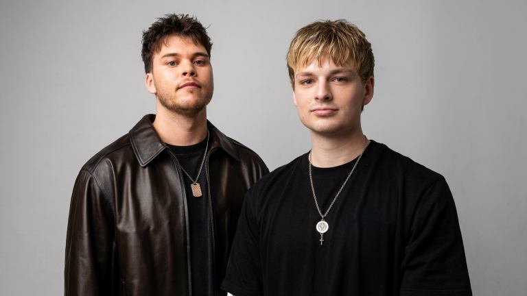 Two young male DJs standing next to each other.