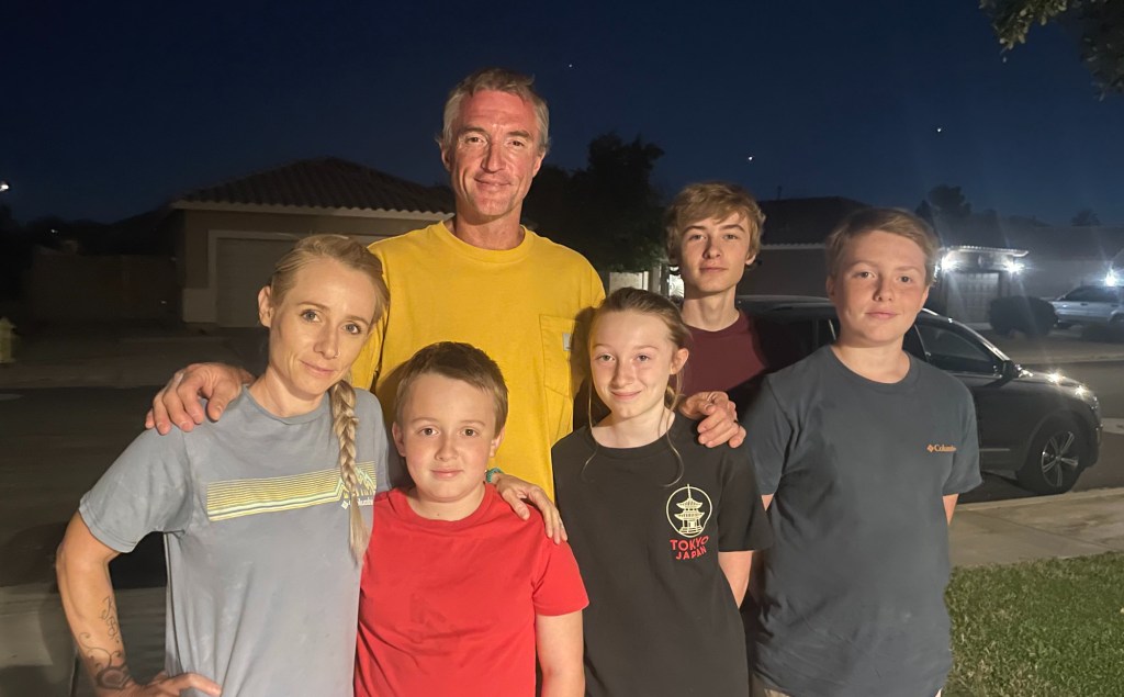 a husband, wife and four children pose for a photo