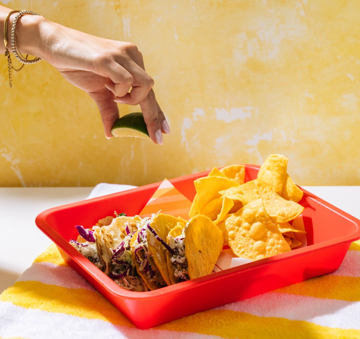 A hand squeezing lime over tacos