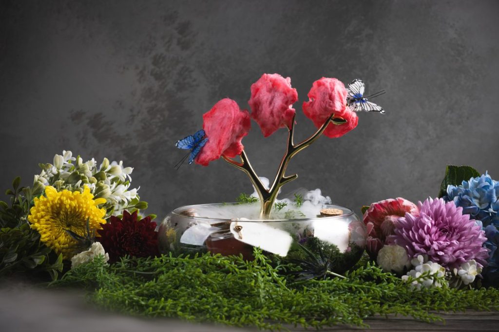 A theatrical drink presentation with cotton candy hung on a brass twig.
