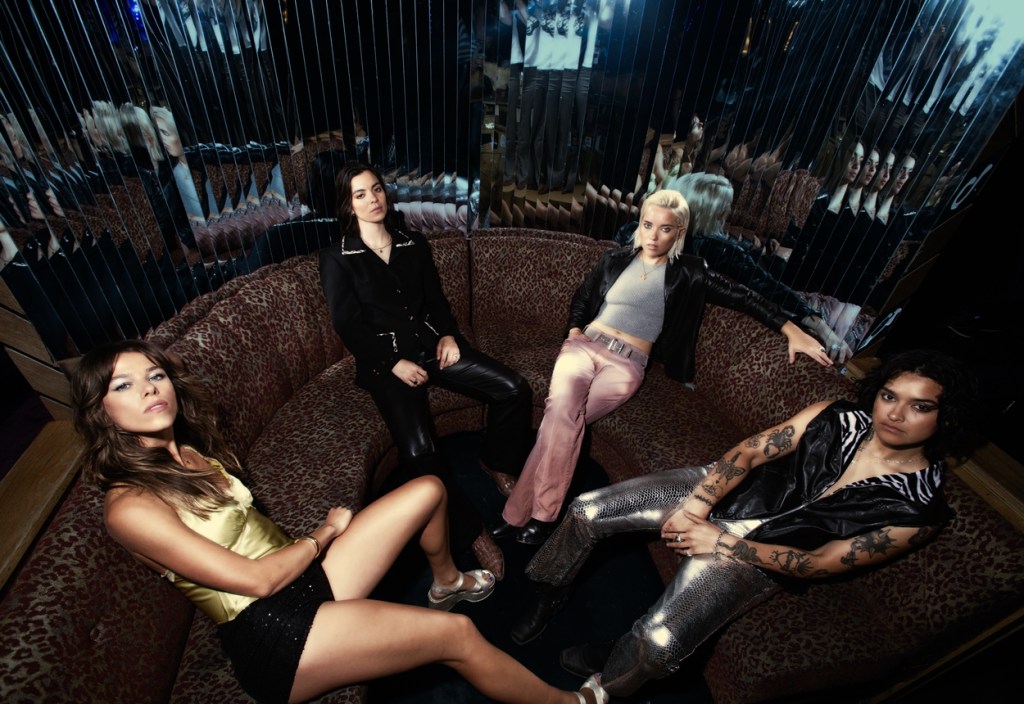 Four female musicians sitting in a VIP booth with mirrored walls.