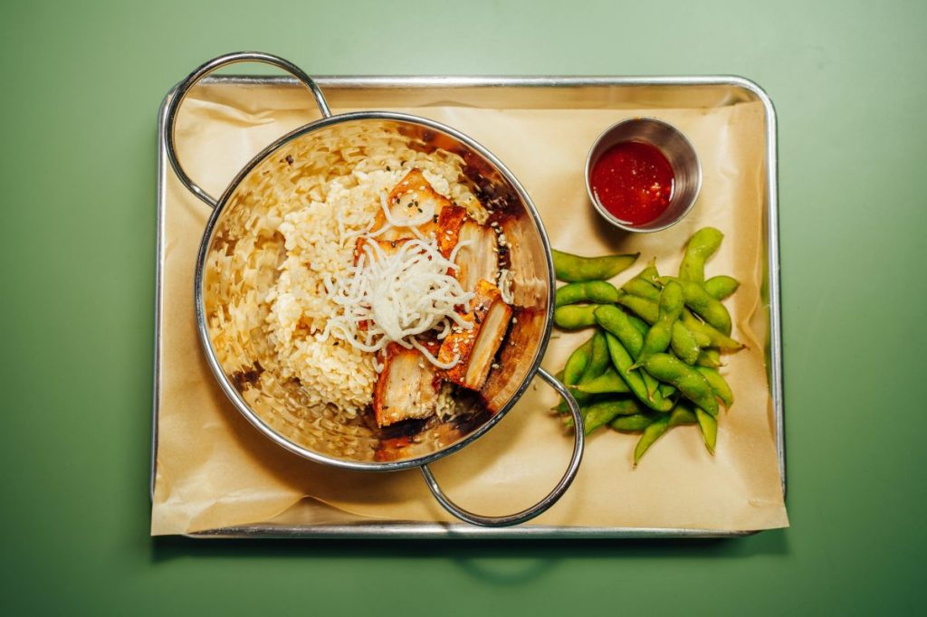 A rice bowl on a tray with a side of edamame.