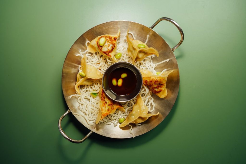 A bowl of dumplings and a dipping sauce.