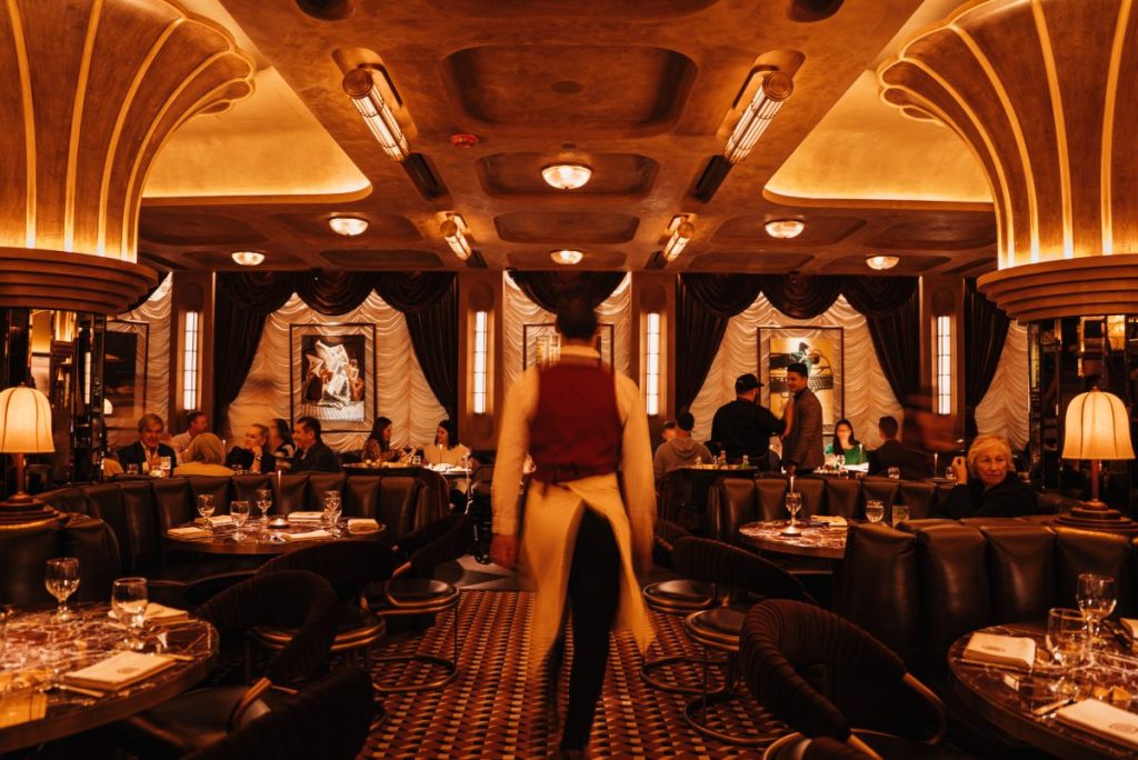A server walks down the aisle of booths in a swanky steakhouse.