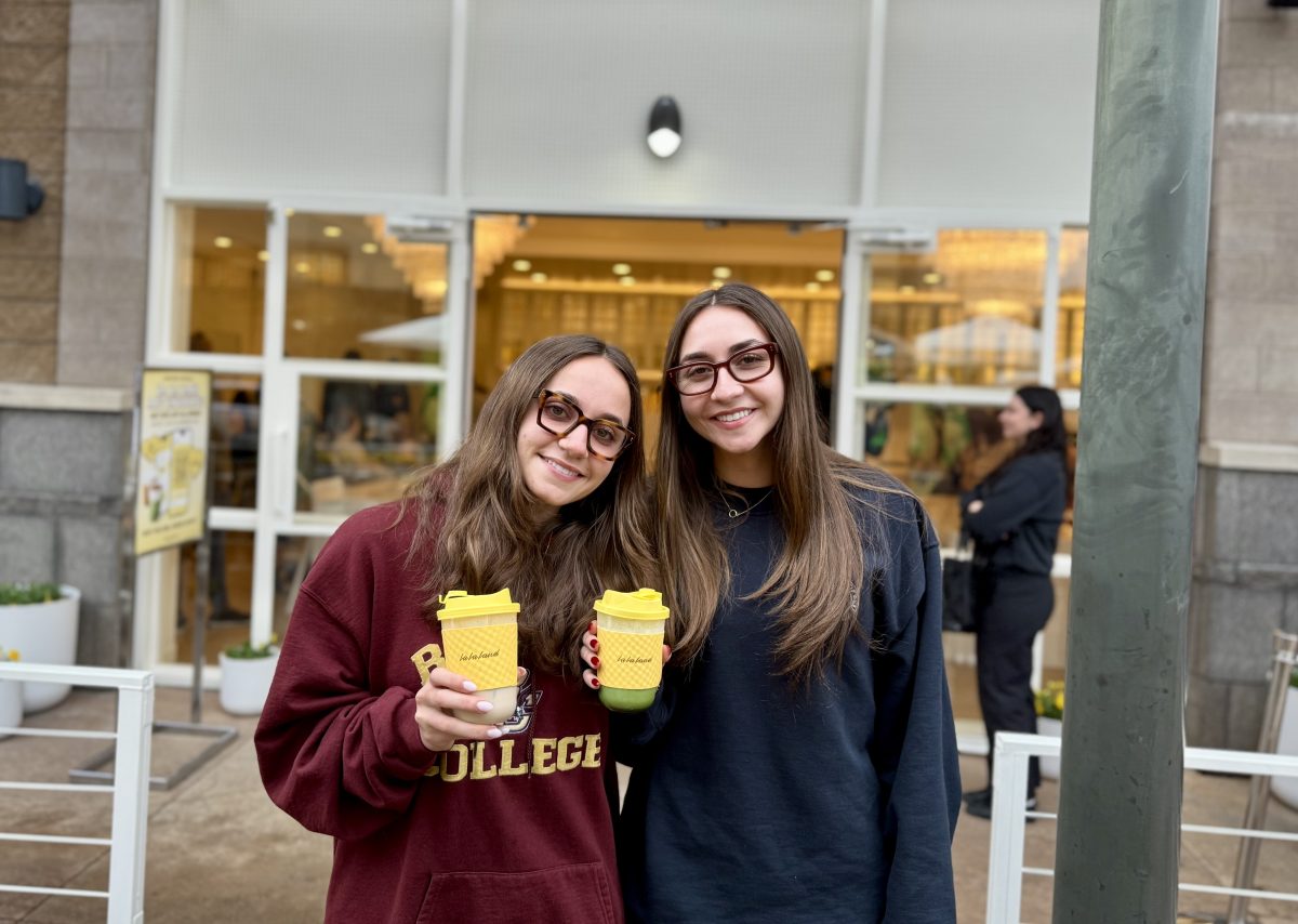 Two women hold coffees from La La Land Kind Cafe.