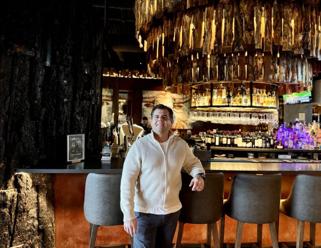 A man posing for a photo at a bar.