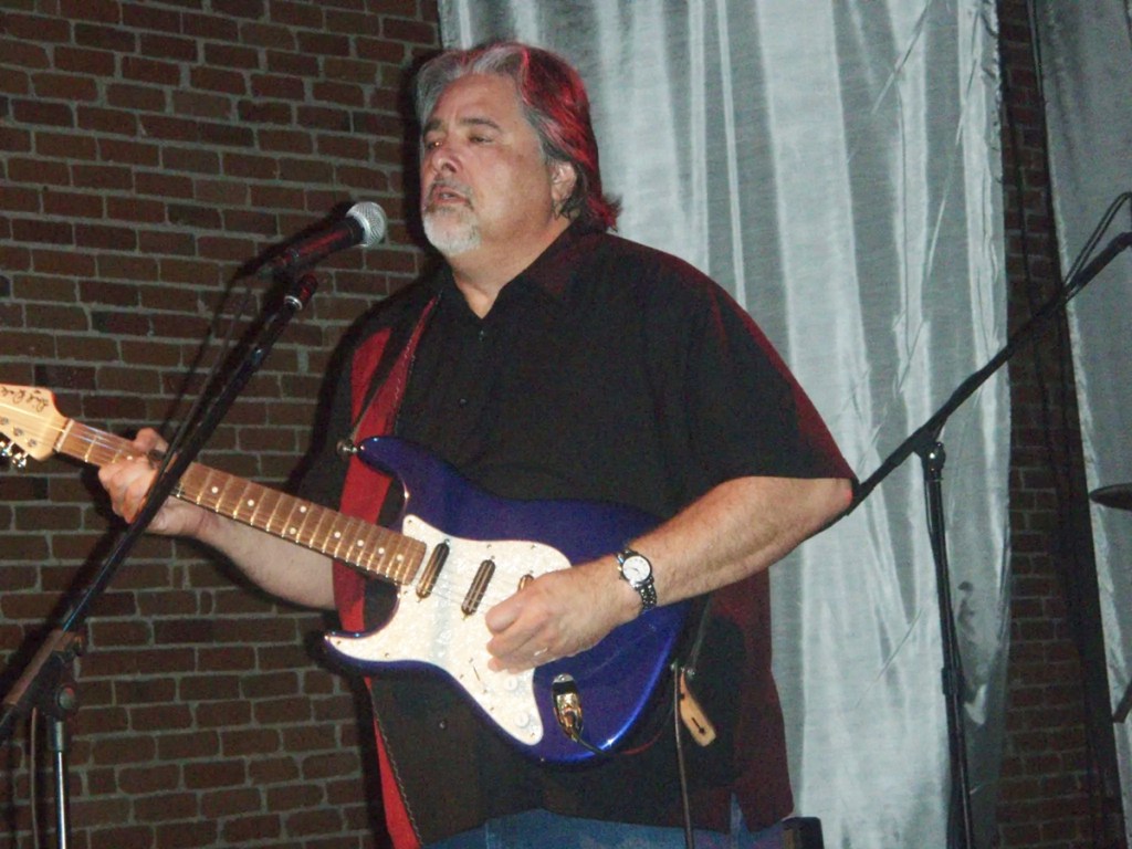 Bluesman Coco Montoya plays a guitar on stage.