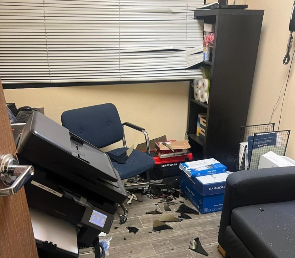 An office strewn with damaged computer equipment and broken glass after a break-in.