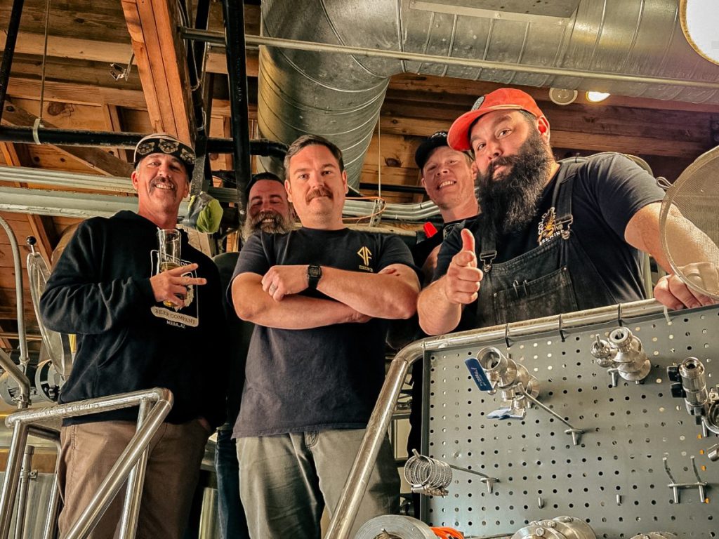 Five brewers standing at the top of a brew kettle.