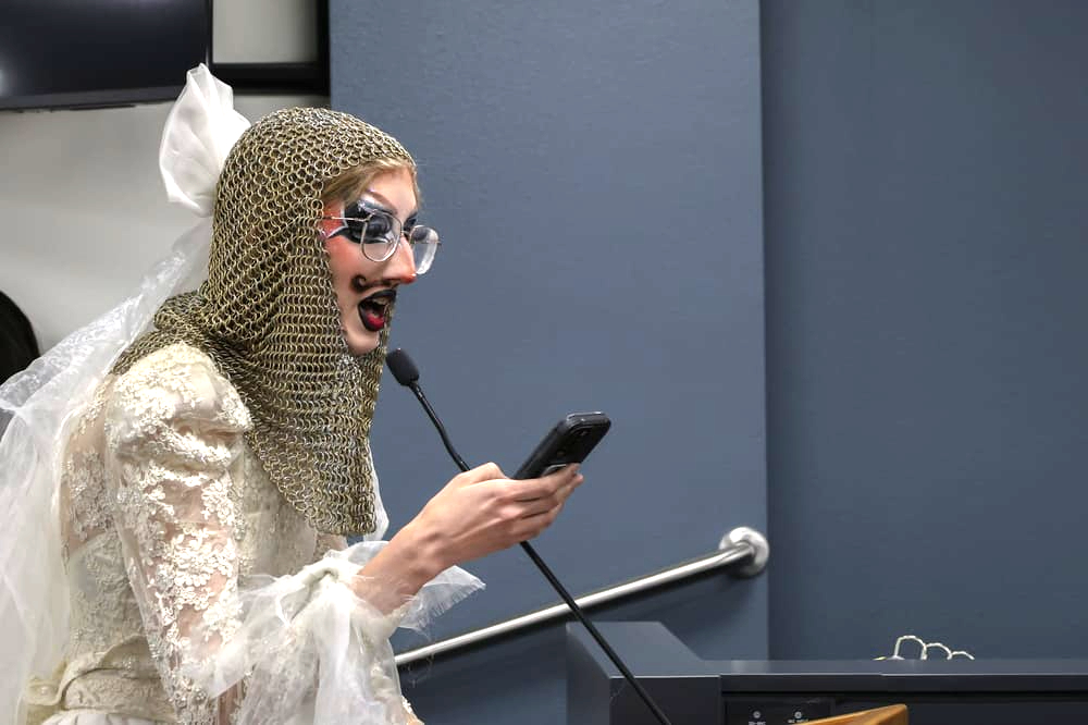 a person in drag speaks at a microphone