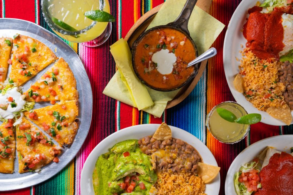 A table full of Mexican food dishes and drinks.
