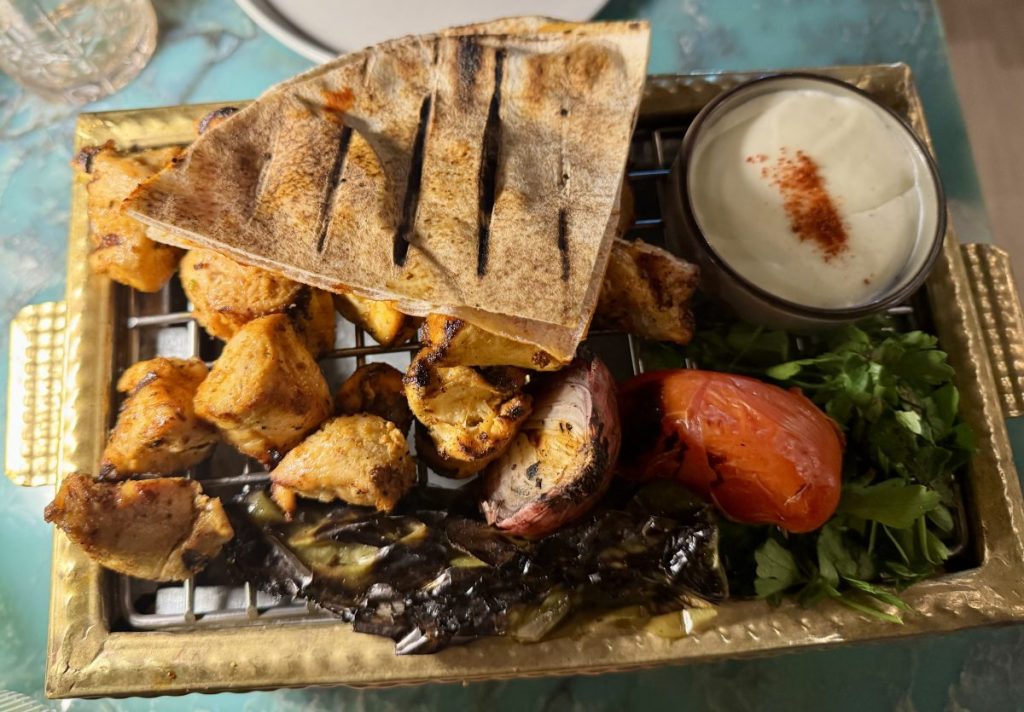 A platter of grilled chicken, vegetables and pita.