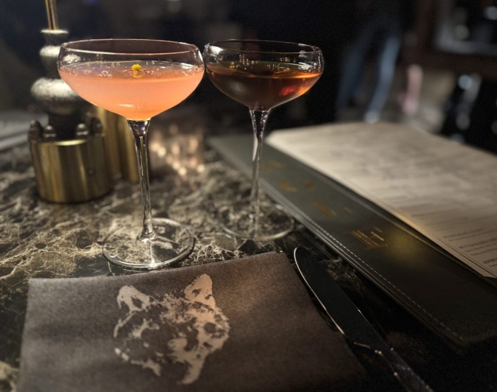 Two martinis in high-stemmed coupe glasses on a table at Wolf by Vanderpump in Scottsdale.