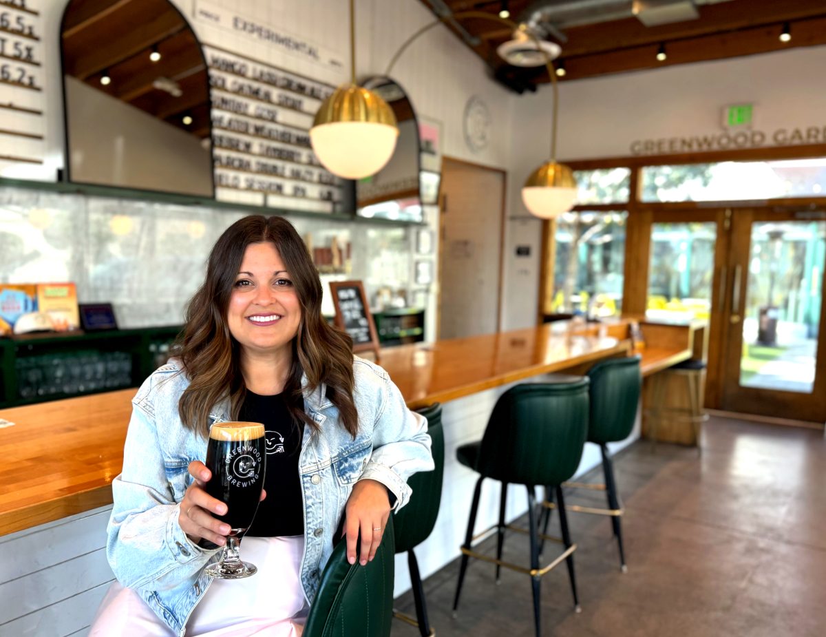 A woman holding a beer in a brewery taproom.