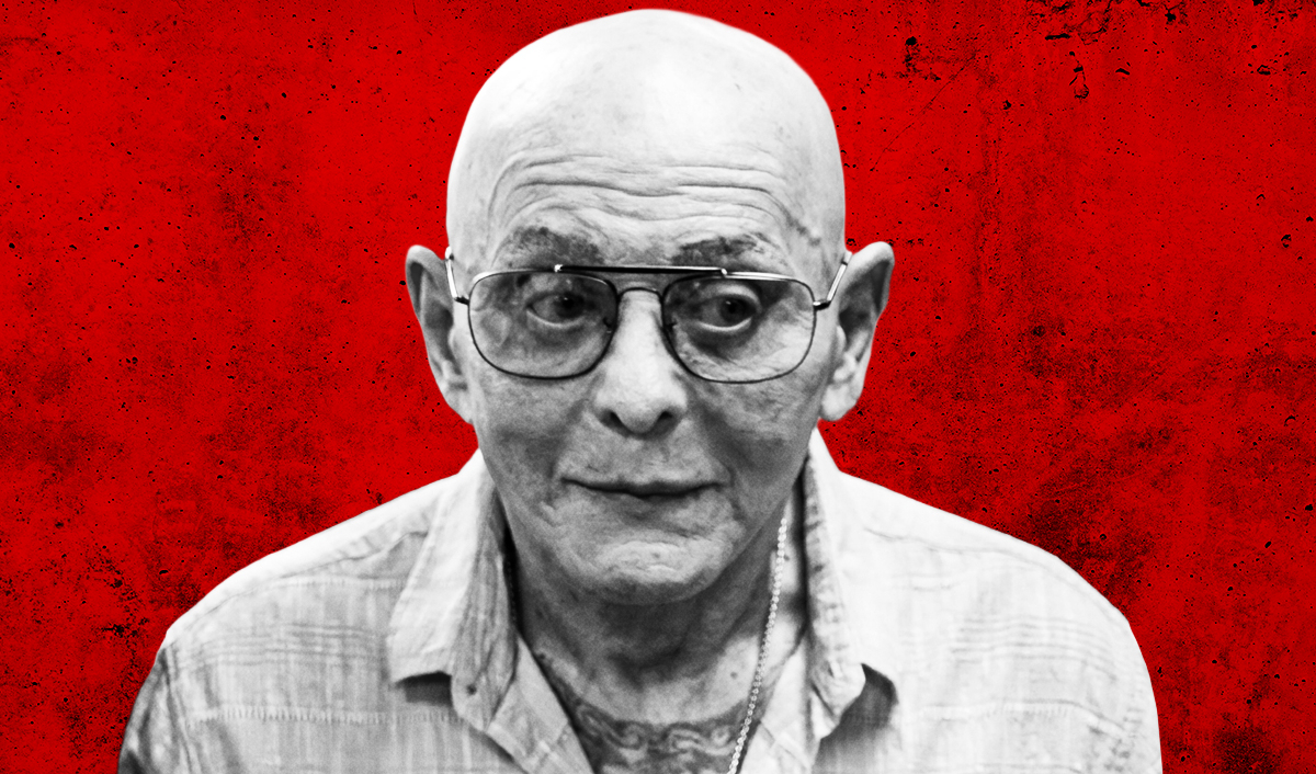 a gray photo of ex-mobster sammy the bull, who is bald and wearing glasses with an open button-down shirt showing chest tattooes