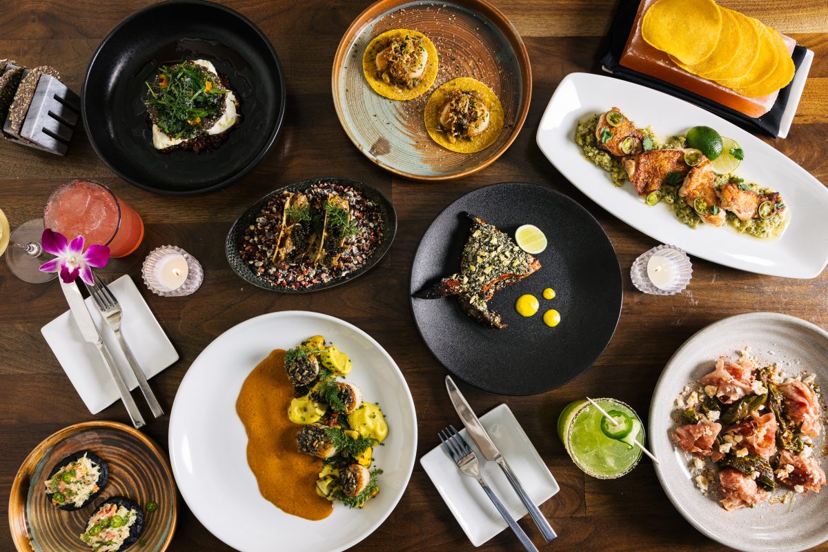 A tablescape filled with plates of food and cocktails.