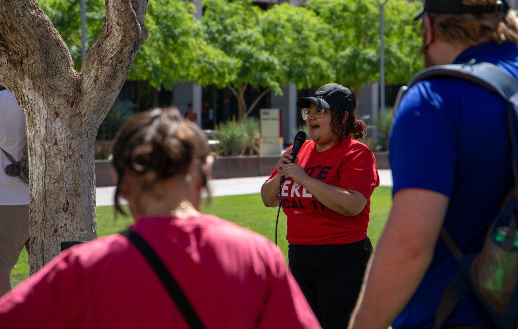 vanessa martinez, a cook at ASU's downtown campus, speaks to a crowd in a red shirt