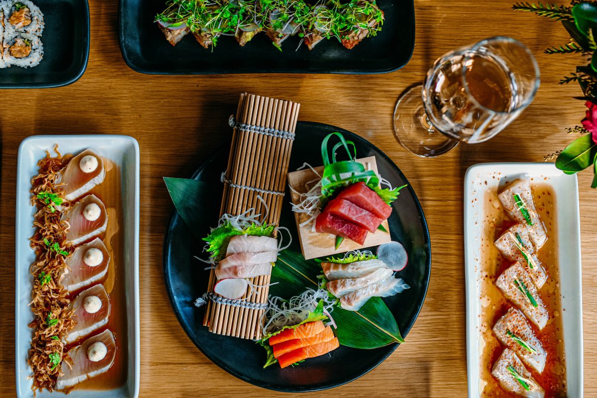 A table filled with plates of sashimi and rolls from Bamboo Sushi.