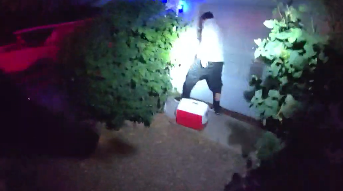 body cam footage of a man in a white shirt walking way, lit by a flashlight