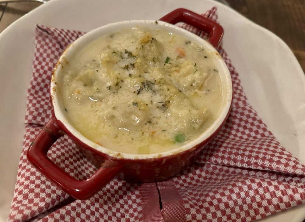 A small enameled pot filled with chicken and dumplings.