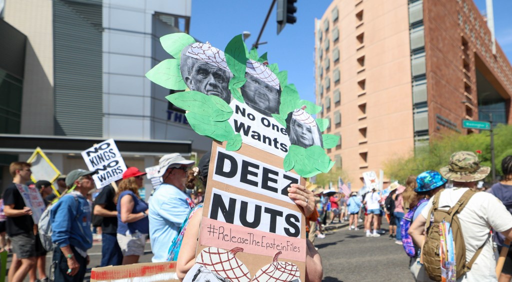 a protester holds a sign that says "no one wants deez nuts" with pictures of robert f. kennedy, jr. j.d. vance and pam bondi