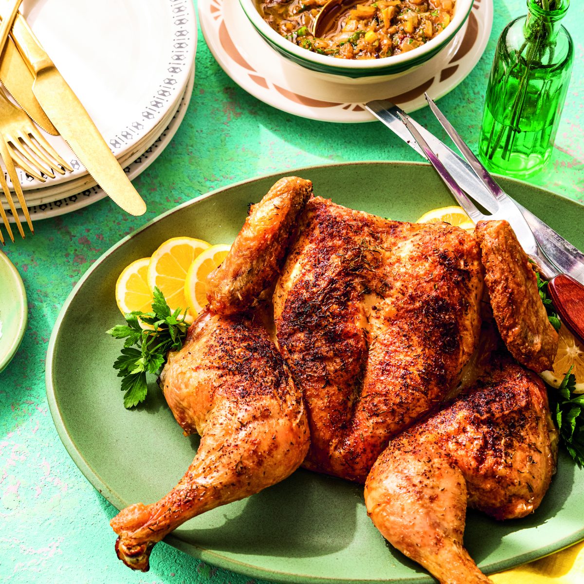 A spatchcocked roast chicken on a platter with a side of onion chutney.