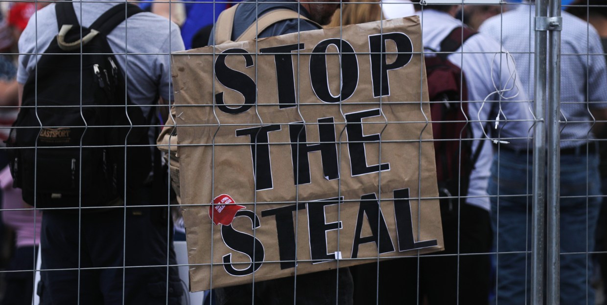 a brown stop the steal sign with a maga hat on it
