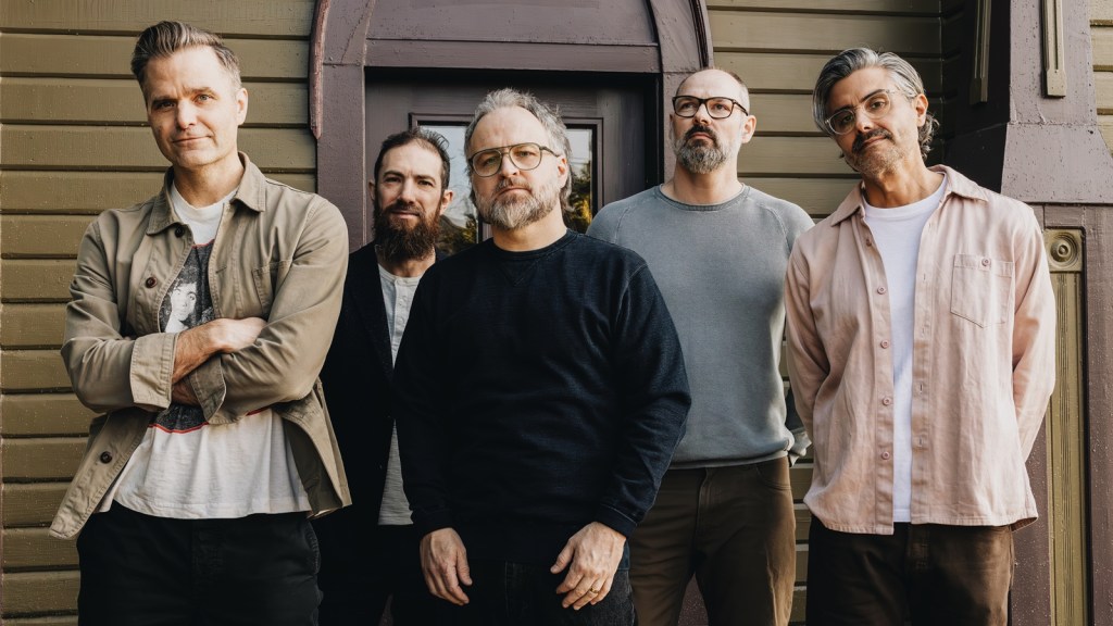 Death Cab for Cutie band members posing outside a building in a promotional photo for their 2026 tour.