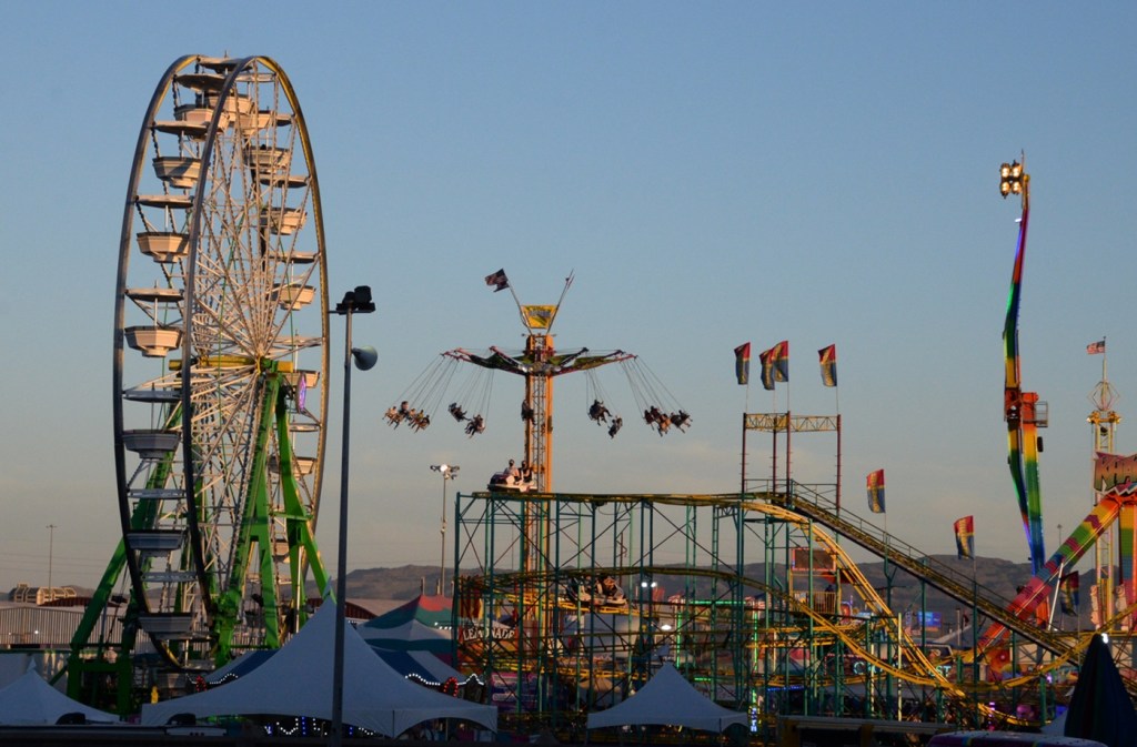 A Ferris wheel and carnival rides at the Maricopa County Fair in Phoenix at sunset.