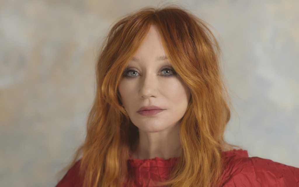 Tori Amos in a red dress in a portrait photo promoting her 2026 tour.