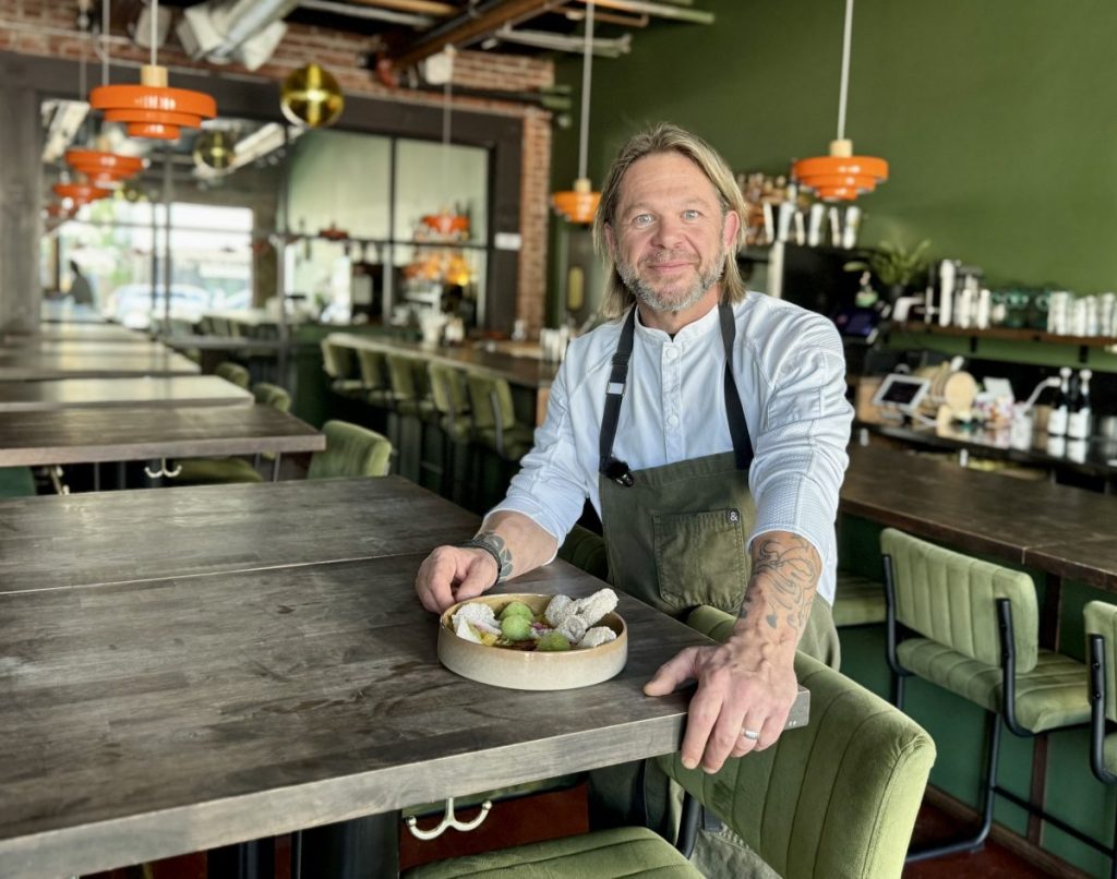 Chef Steven "Chops" Smith stands with a plate of crudo in the dining room of Pretty Penny