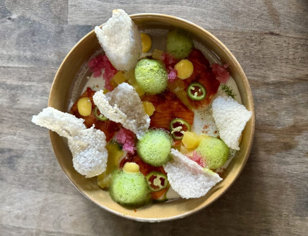 An abstract crudo with cilantro foam, al pastor glazed fish and chicarrones.
