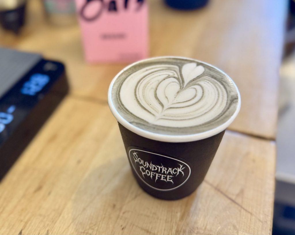 A black charcoal latte, with the heart latte art in focus.
