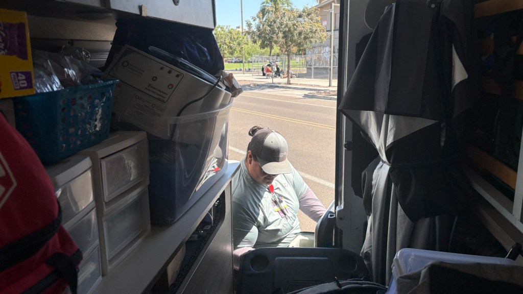 Madril grabs water from the back of a van to hand out to homeless people hanging out at Margaret T. Hance Park.