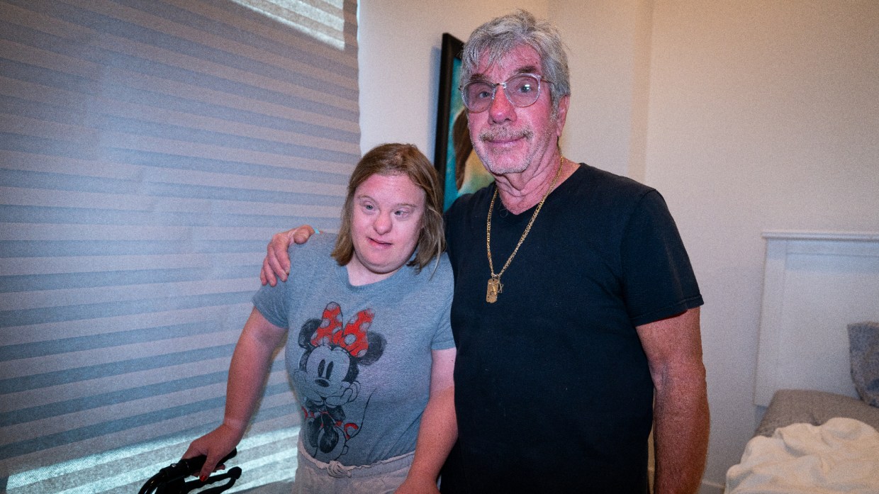 michael marion and his adult daughter dana. michael wears a black shirt and has gray hair and glasses. dana is using a walker and wears a minnie mouse shirt