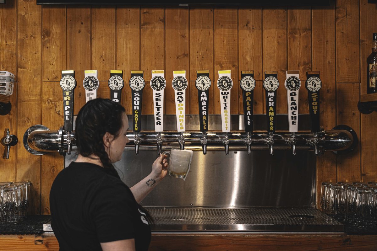 A woman pours a beer into a dimpled mug.
