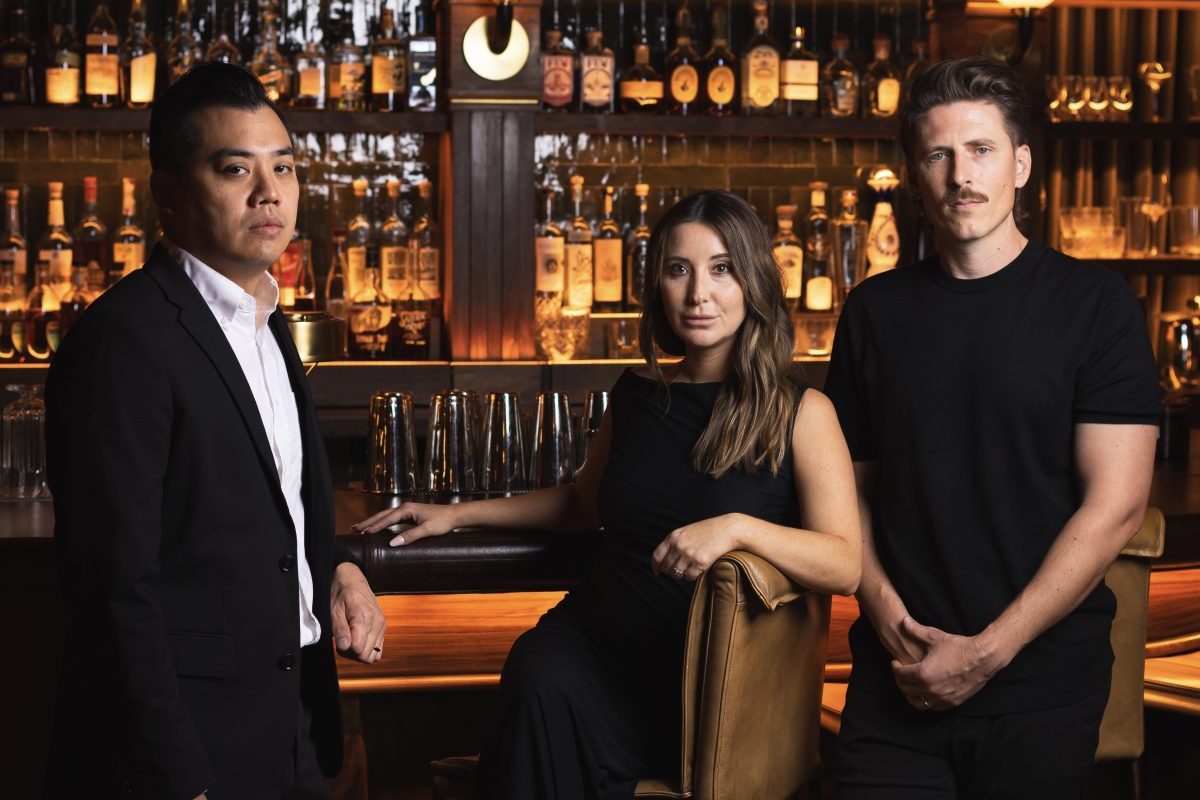 Pretty Decent Concepts founders Thor Nguyen, Kaitlin Myers and Teddy Myers pose in front of a bar.