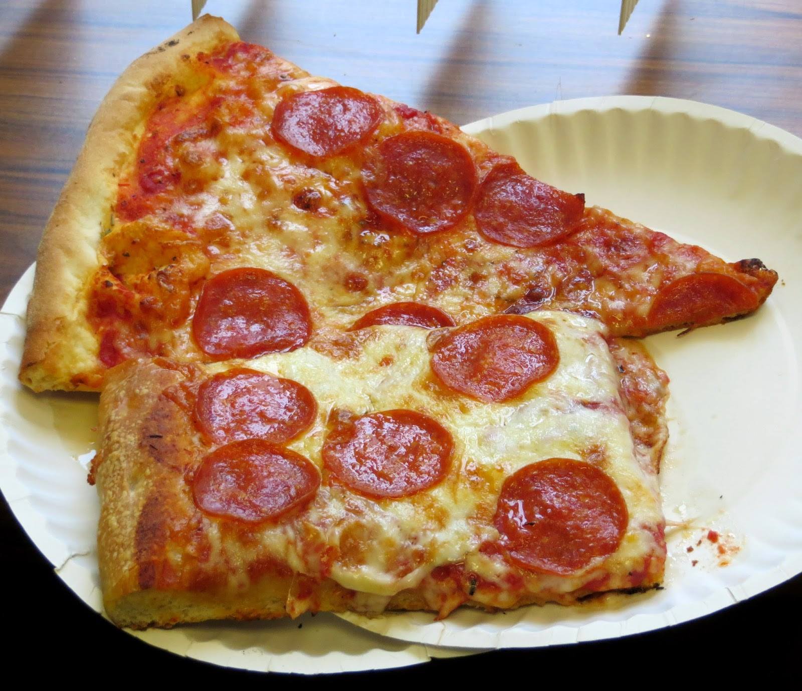 Slices of Sicilian and New York-style pepperoni pizza on a paper plate.