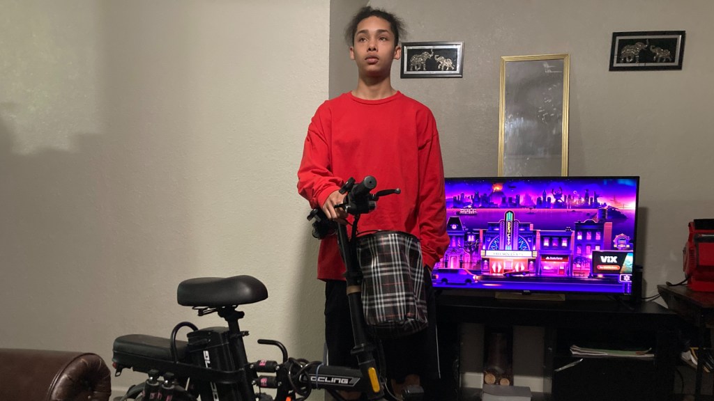 rayvion johnson stands with his ebike in his living room