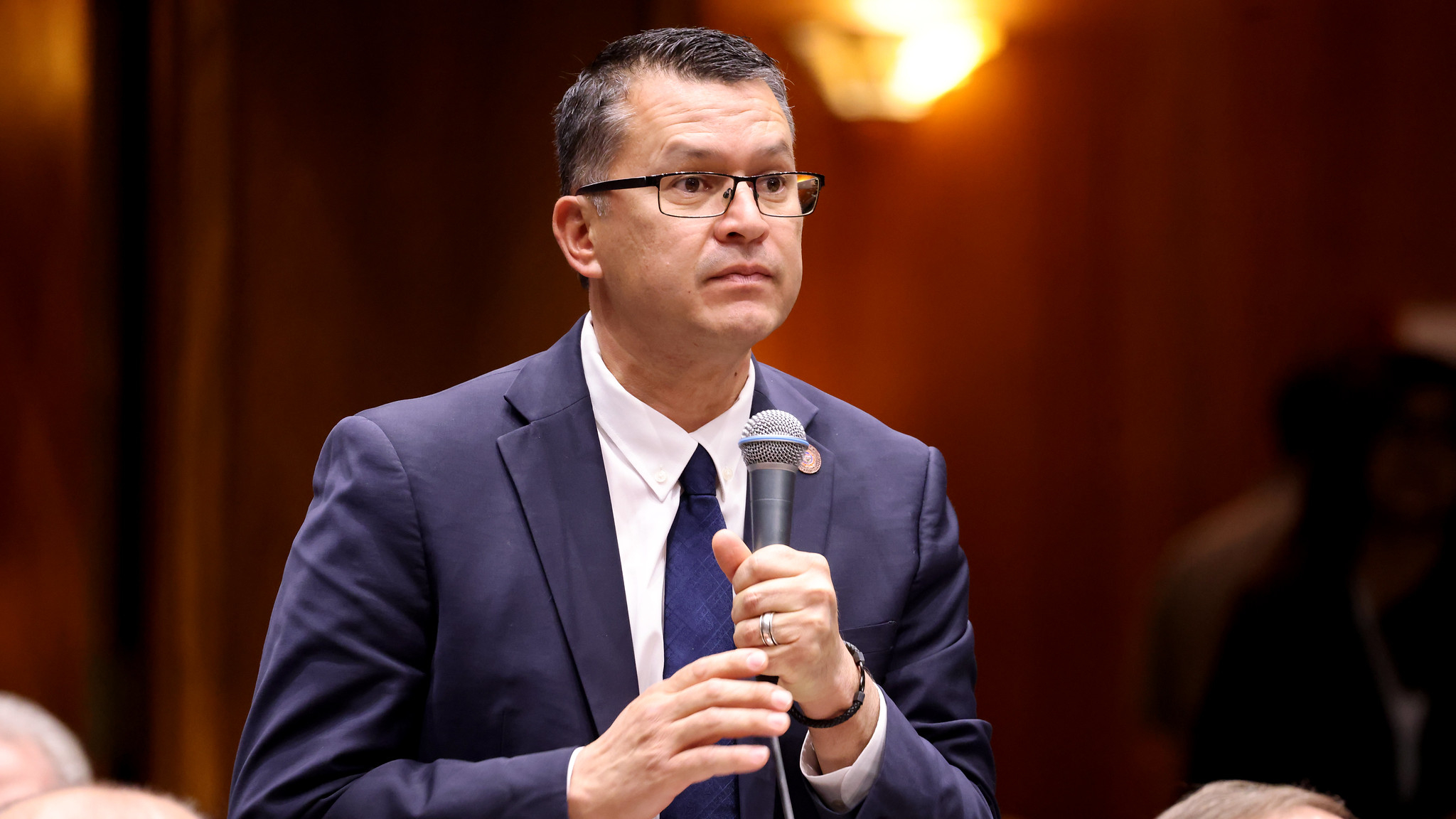 tony rivero holds a microphone in a suit