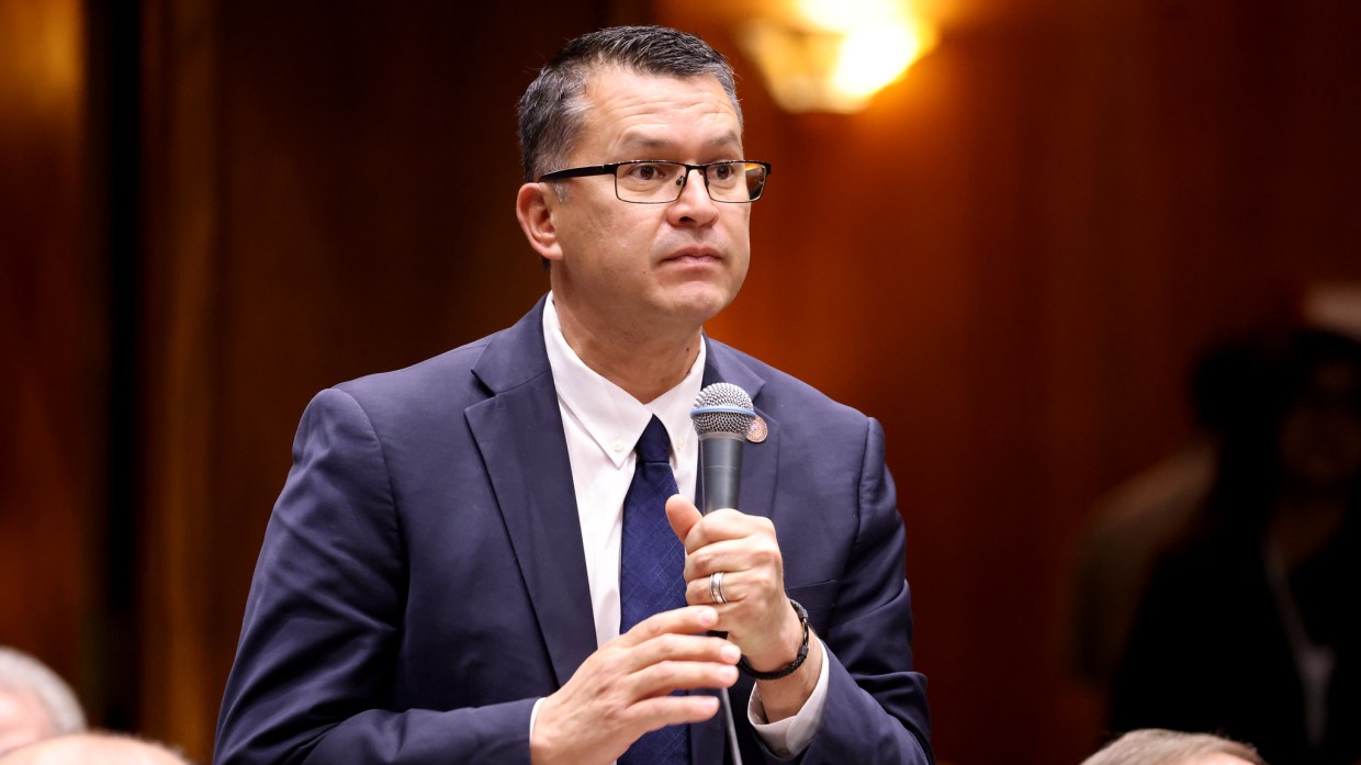 tony rivero holds a microphone in a suit