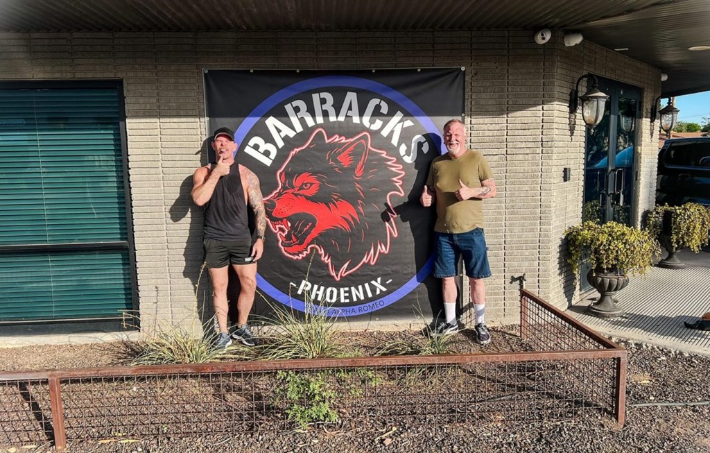 Barracks Bar co-owners Scott Murchison and Matthew Moody stand in front of the bar’s Phoenix location logo