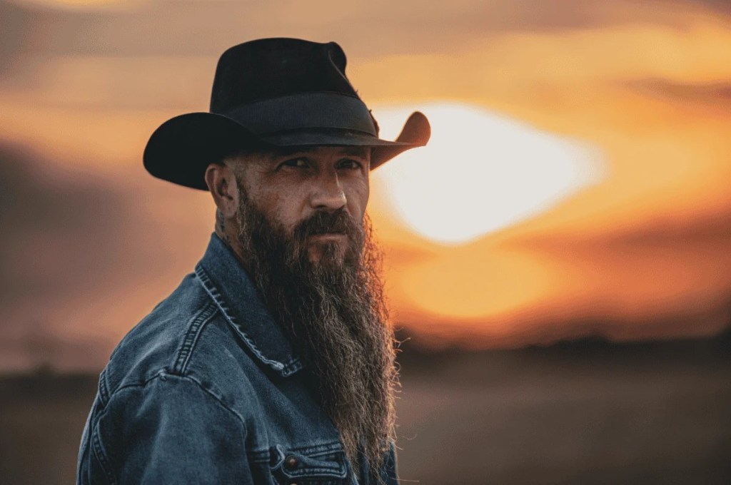 Cody Jinks poses for a publicity photo in front of a sunset in advance of this concert at Arizona Bike Week.