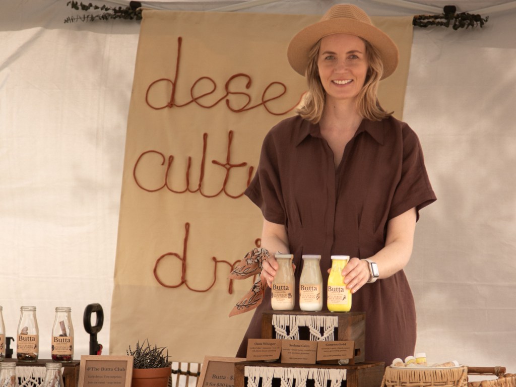 A woman poses at a farmers market booth.