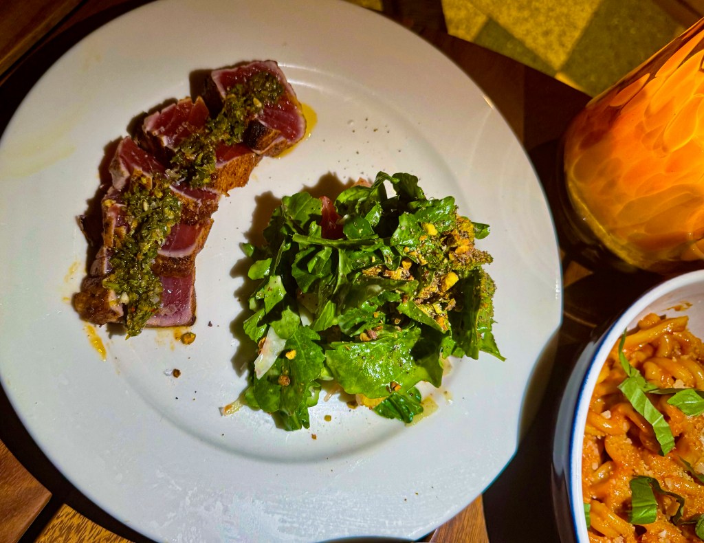 A plate of seared tuna with an arugula salad.