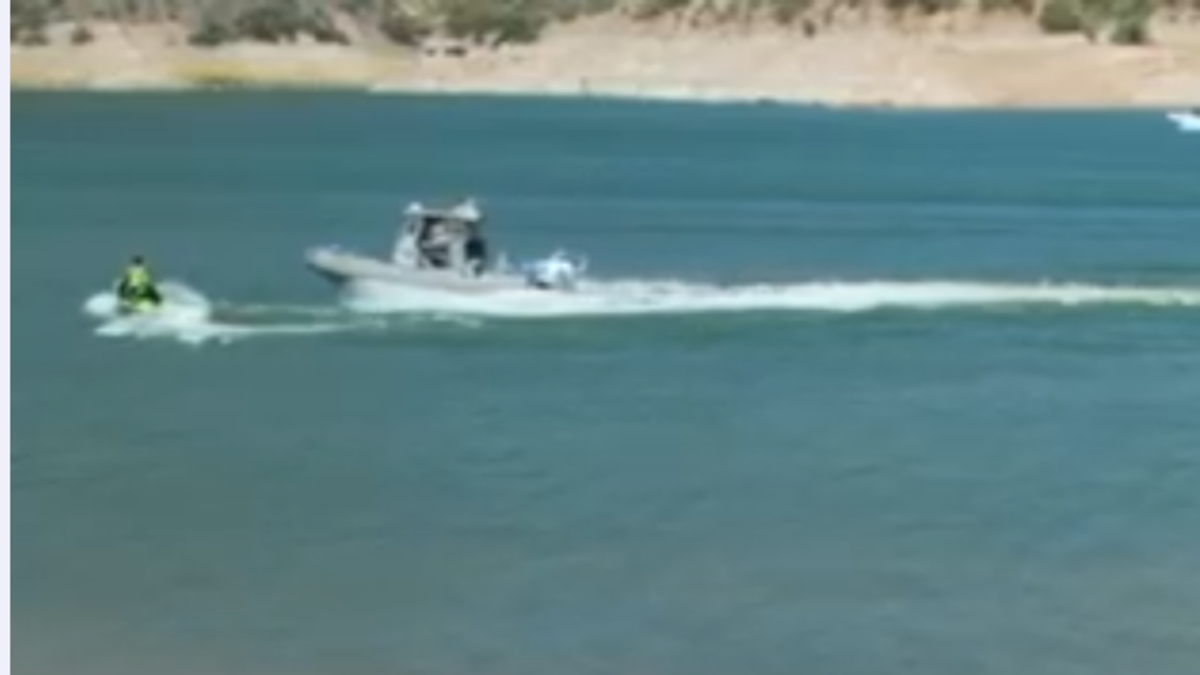 a boat approaches a collision with a man on a jetski