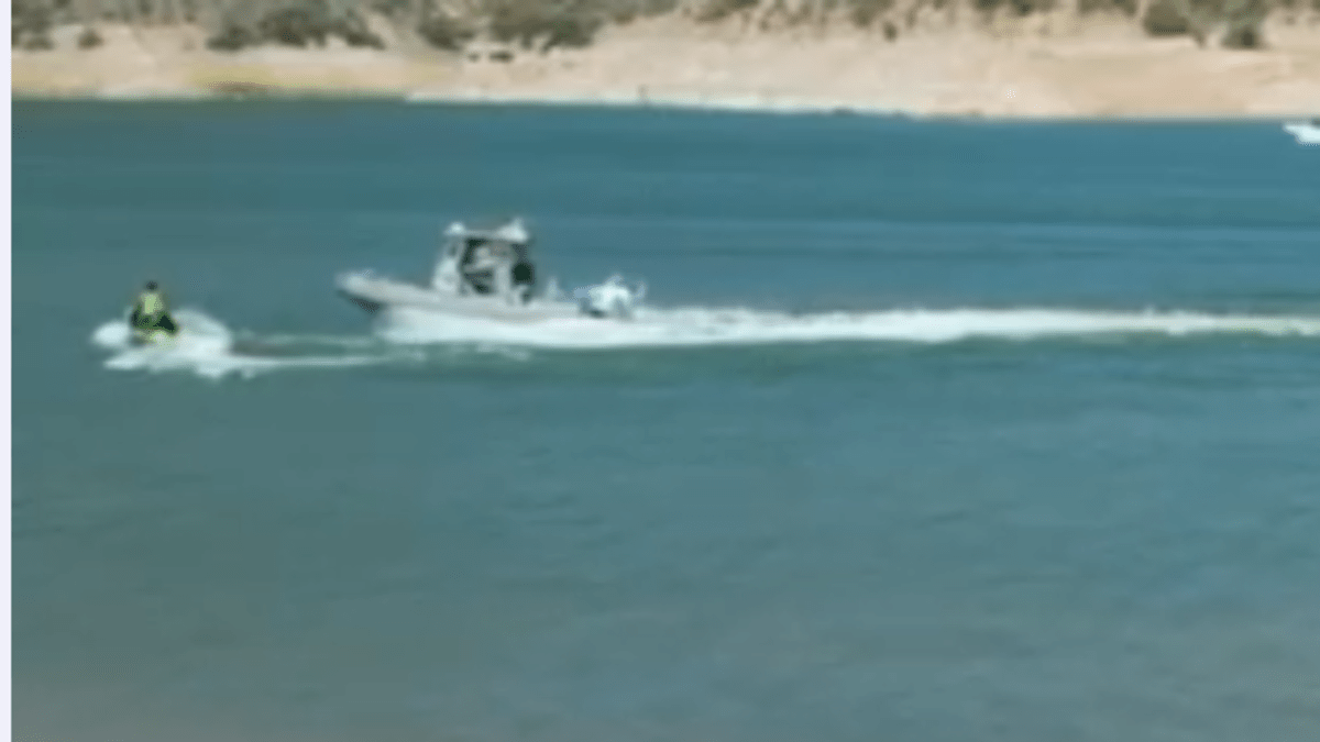 a boat approaches a collision with a man on a jetski